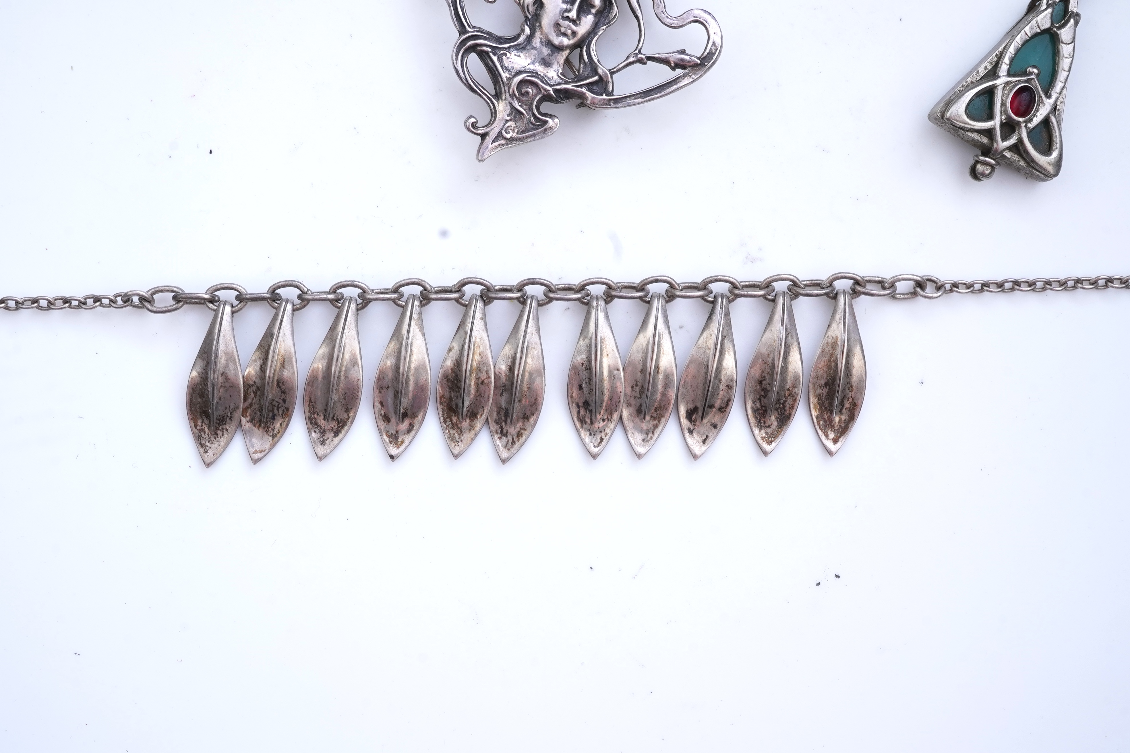 A collection of three silver chains and an Art Nouveau brooch, early 20th century